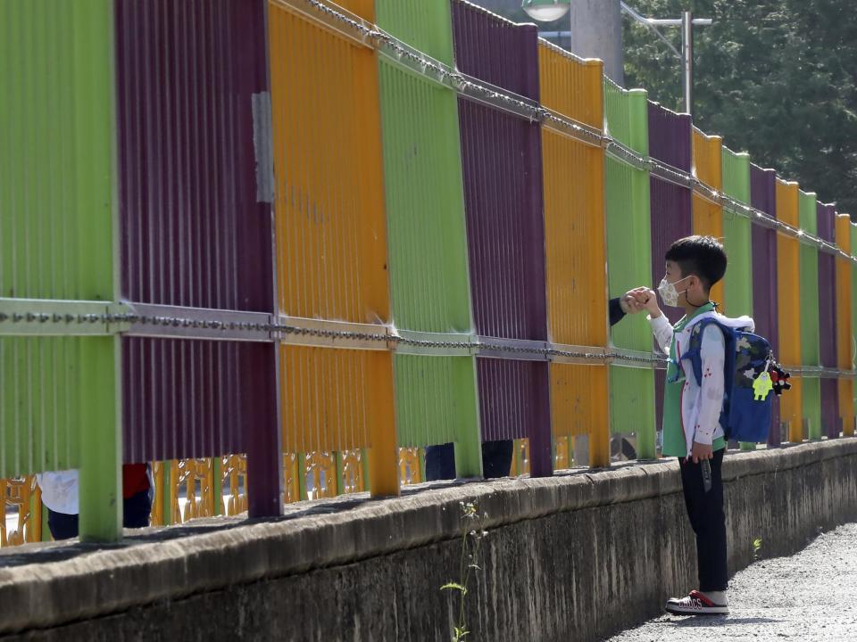 A pupil wearing a face mask to help protect against the spread of the new coronavirus holds his mother's hand through a fence as he arrives at the Ochi Elementary School in Gwangju, South Korea, Friday, May 29, 2020: AP