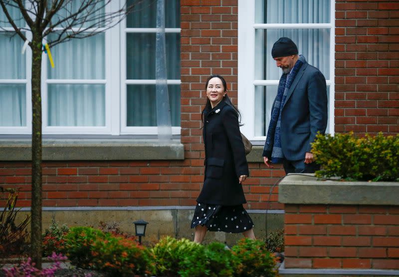 Huawei Chief Financial Officer Meng Wanzhou walks with a member of her security as she leaves her home to attend her extradition hearing in Vancouver