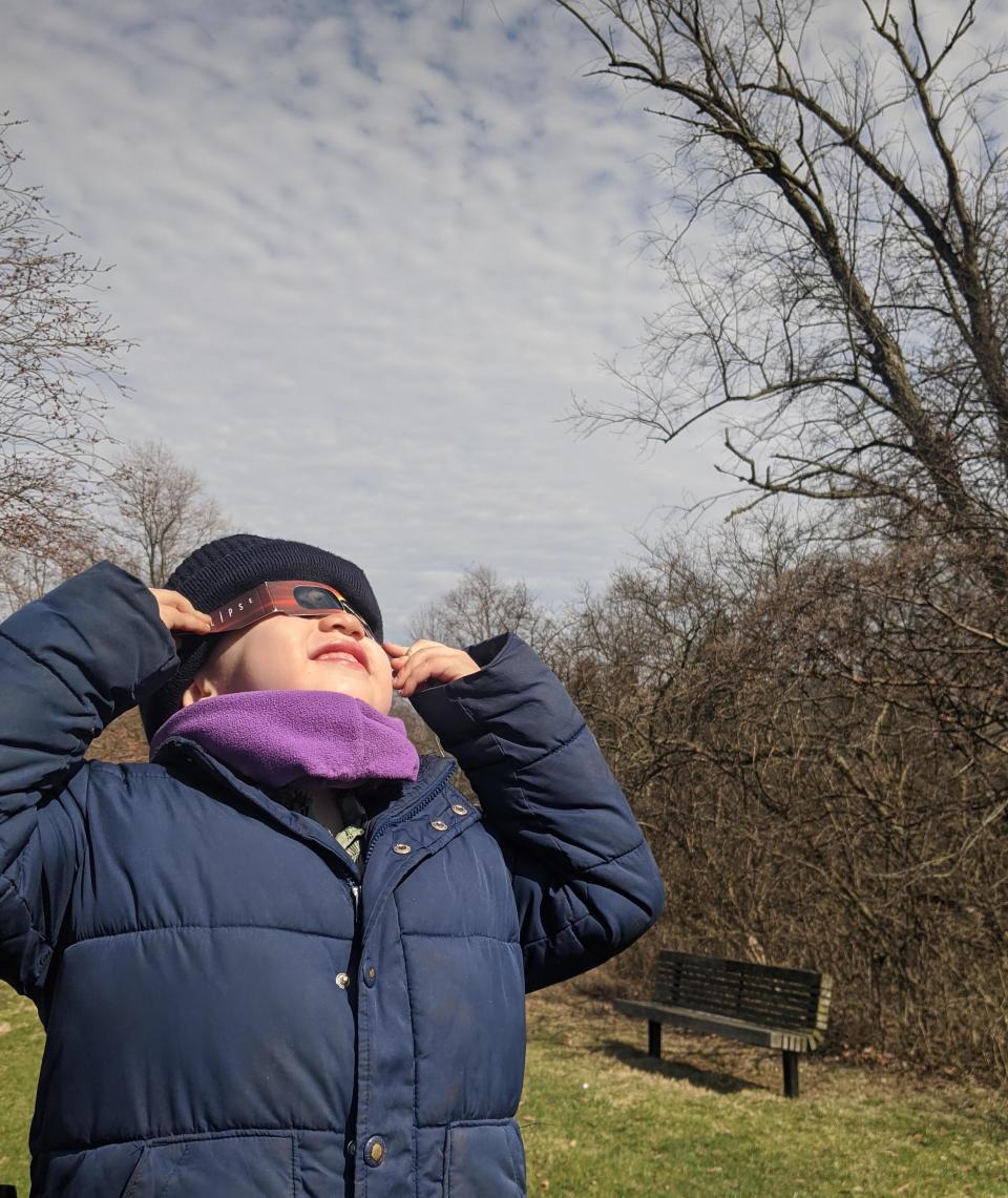 A boy looks up at the sun wearing solar glasses on April 8, 2024