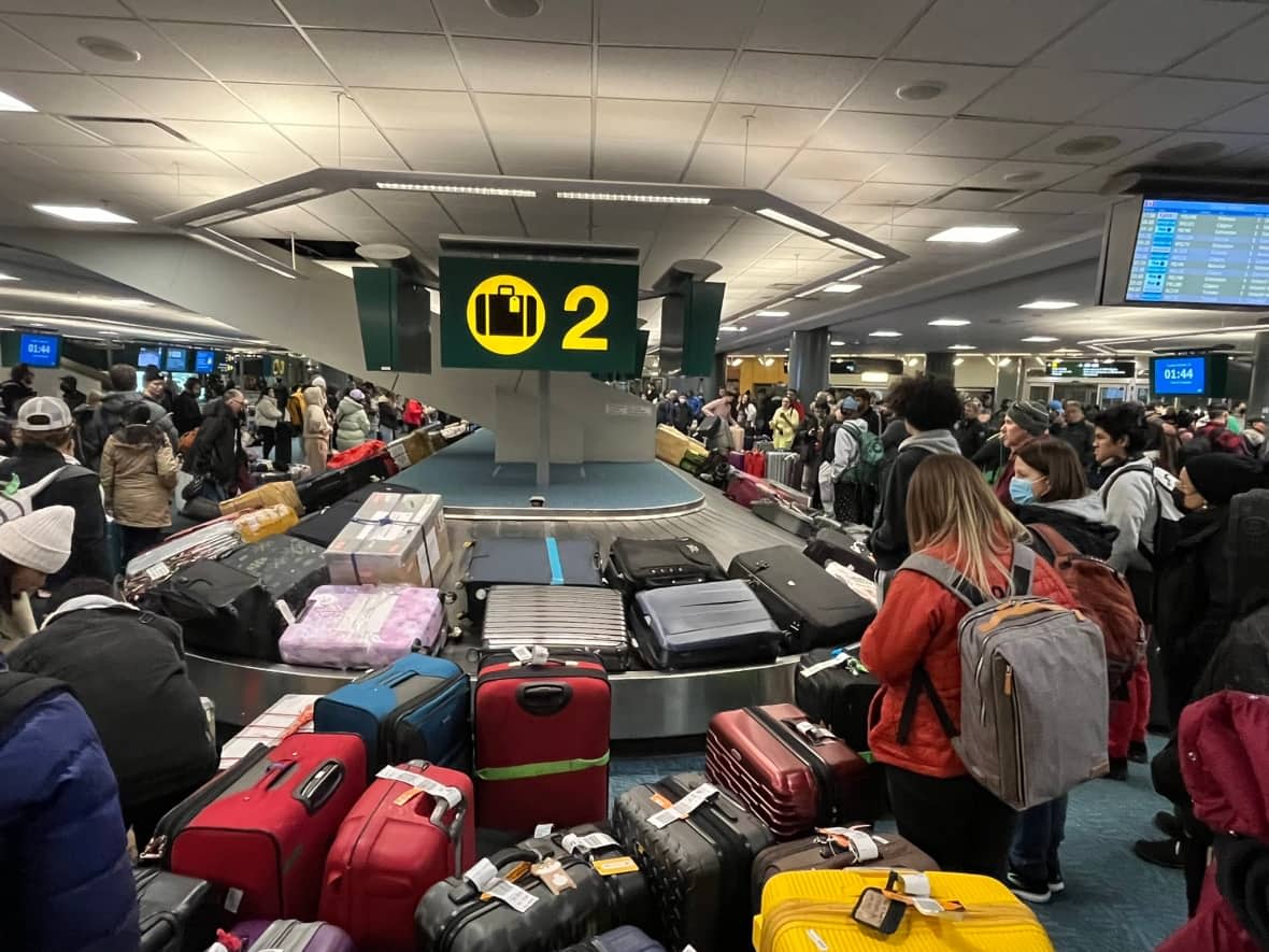 A mess of luggage and passengers at a baggage terminal inside Vancouver International Airport amid mass cancellations and suspended flights during a snowstorm on Dec. 19, 2022. (Supplied by Craig Minielly - image credit)