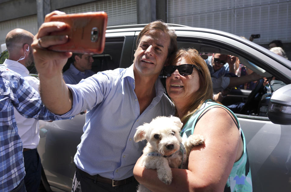 El candidato presidencial por el Partido Nacional, Luis Lacalle Pou, a la izquierda, posa con una seguidora después de votar en Canelones, Uruguay, el domingo 24 de noviembre de 2019. (Foto AP/Matilde Campodonico)