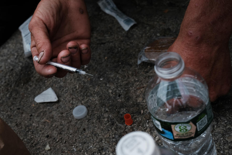 An addict prepares to inject a mix of heroin and fentanyl on a street in Philadelphia