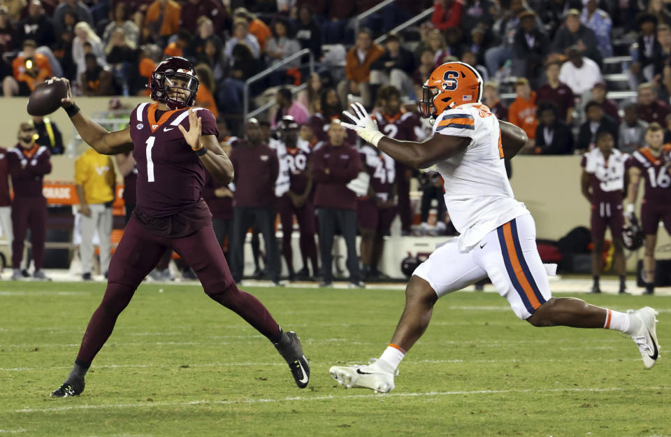 Virginia Tech quarterback Kyron Drones (1) throws while chased by Syracuse defender Caleb Okechukwu (4) during the second half of an NCAA college football game Thursday, Oct. 26, 2023, in Blacksburg, Va. (Matt Gentry/The Roanoke Times via AP)