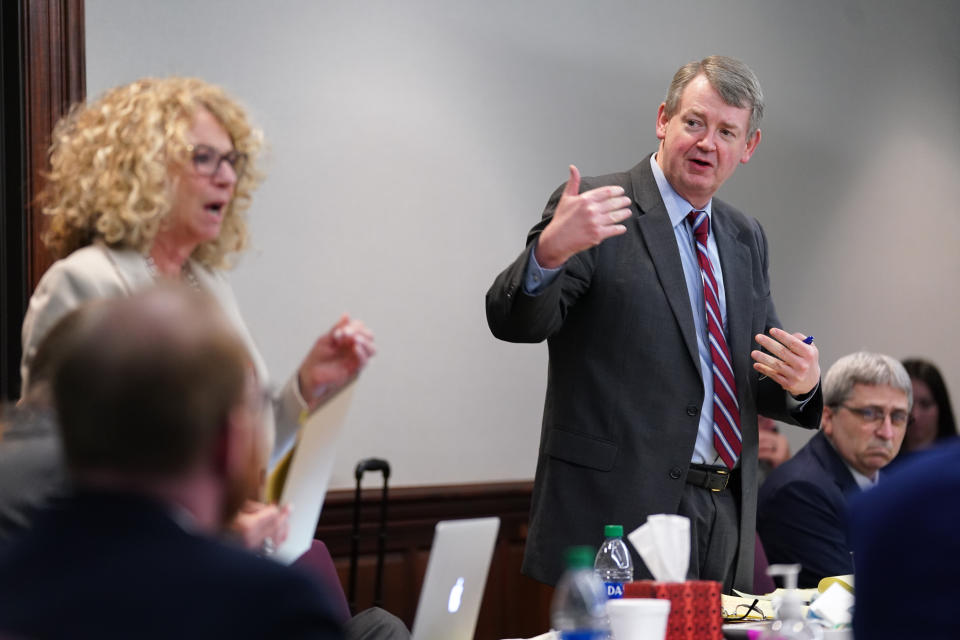 Defense attorneys Kevin Gough and Laura Hogue, both standing as others in the room sit listening, speak during a break in the Ahmaud Arbery death trial.