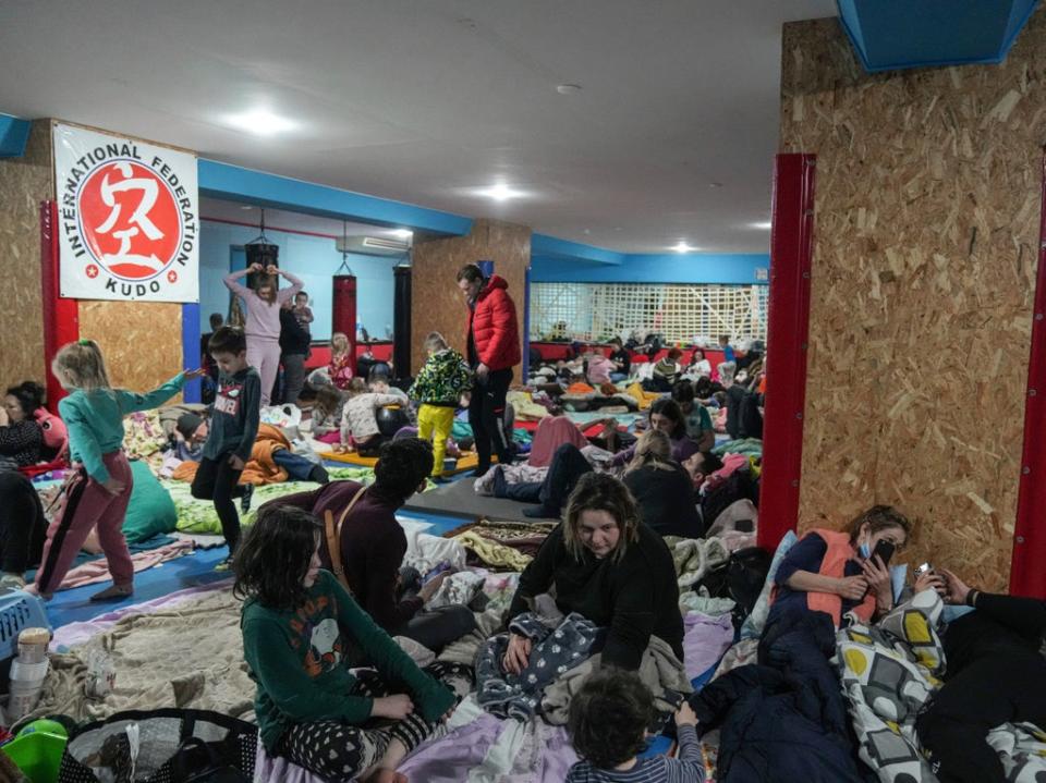 People sit on the floor in an improvised bomb shelter at sports centre, which can accommodate up to 2,000 people, in Mariupol, Ukraine (Evgeniy Maloletka/AP)