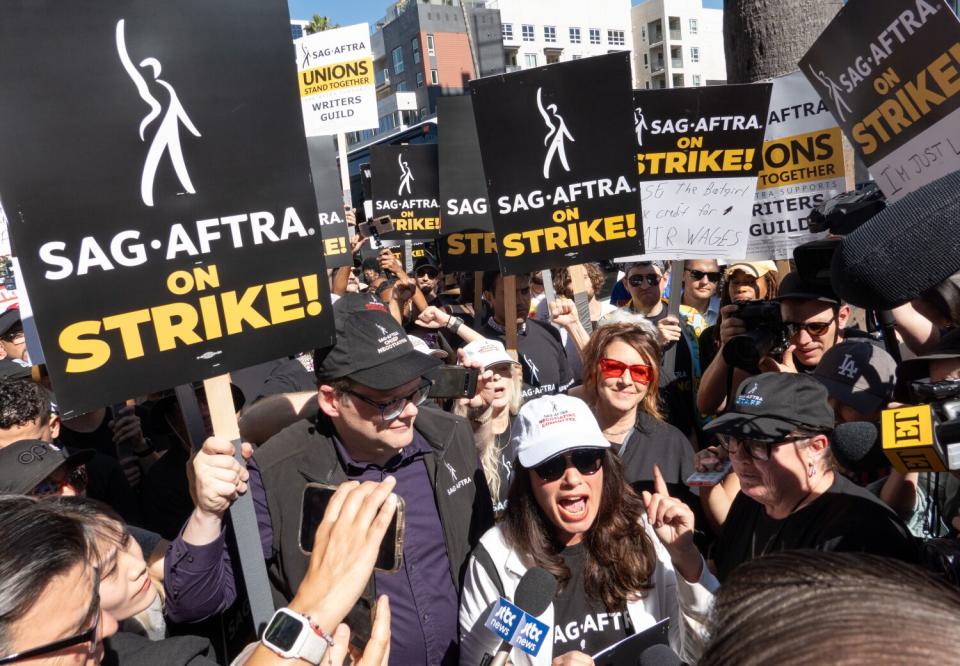 Sign-wielding striking actors gather on a picket line.