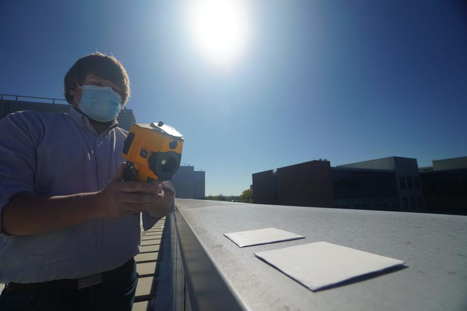 Purdue University researcher Joseph Peoples uses an infrared camera to compare the cooling performance of white paint samples on a rooftop.