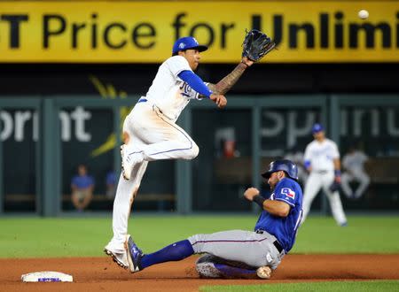 Jun 20, 2018; Kansas City, MO, USA; Kansas City Royals shortstop Adalberto Mondesi (27) jumps for the ball as Texas Rangers third baseman Joey Gallo (13) slides into second base in the eighth inning at Kauffman Stadium. Mandatory Credit: Jay Biggerstaff-USA TODAY Sports