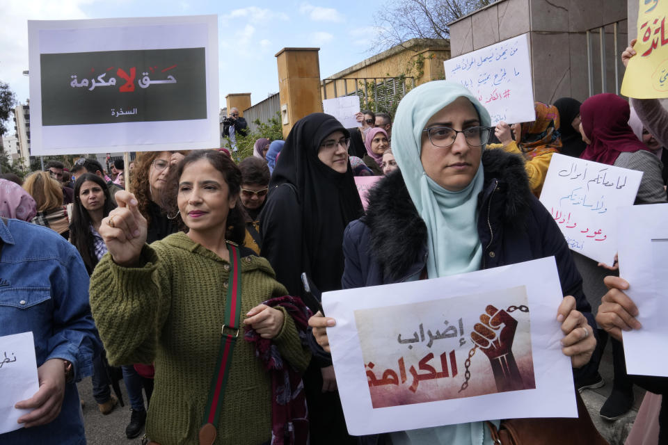 Lebanese teachers hold Arabic placards that read: "Right is not a good deed" and on left, the "Strike of dignity," during a protest outside the Education Ministry, in Beirut, Lebanon, Monday, March 6, 2023. Lebanon's education system is in crisis. Public schools have been open for fewer than 50 days this school year because teachers are on strike, protesting dramatic currency devaluations that slashed their salaries to about $20 a month. (AP Photo/Hussein Malla)