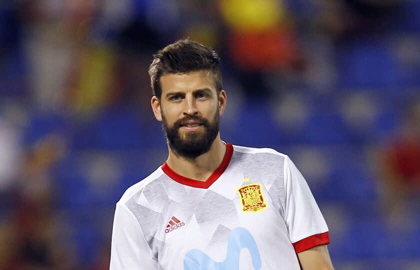 A man with brown hair and facial hair in a soccer jersey