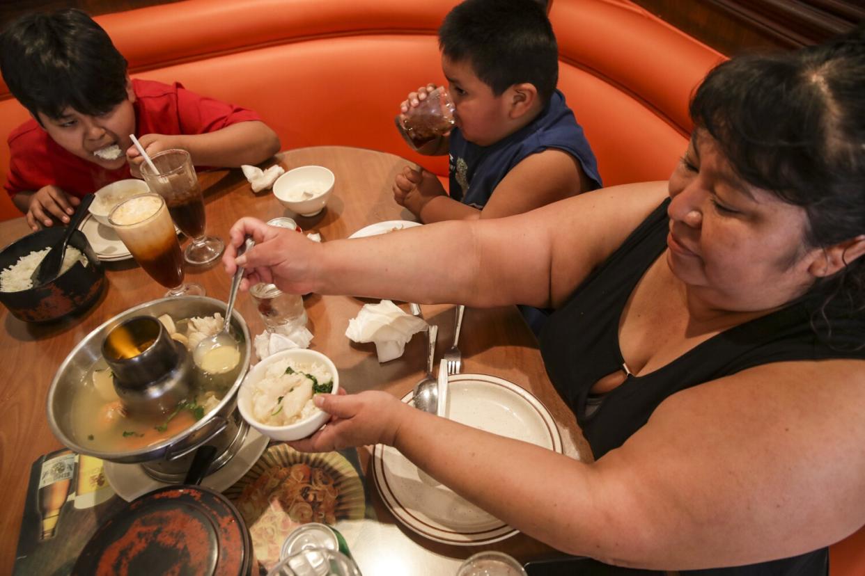 Juana Aspuac, bottom right, and her family have lunch at Ocha Classic restaurant.