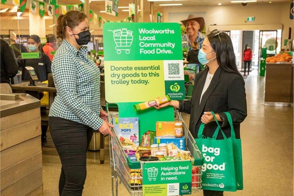 Woolworths shopper hands dried good to staff member at food drive trolley. Source: Woolworths Group