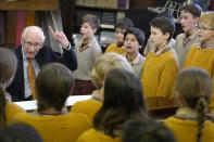 Pupils in the choir gather around the piano to sing with Richard Townend at Hill House School in London, a school where Britain's King Charles III was a pupil, Thursday, April 20, 2023. King Charles III hasn’t even been crowned yet, but his name is already etched on the walls of Hill House School in London. A wooden slab just inside the front door records Nov. 7, 1956, as the day the future king enrolled at Hill House alongside other notable dates in the school’s 72-year history. (AP Photo/Kirsty Wigglesworth)