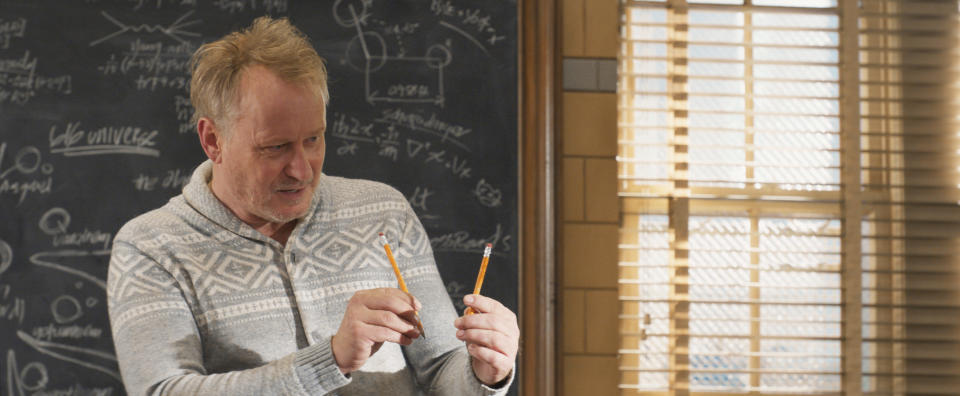 Erik in front of a chalkboard holding up two pencils