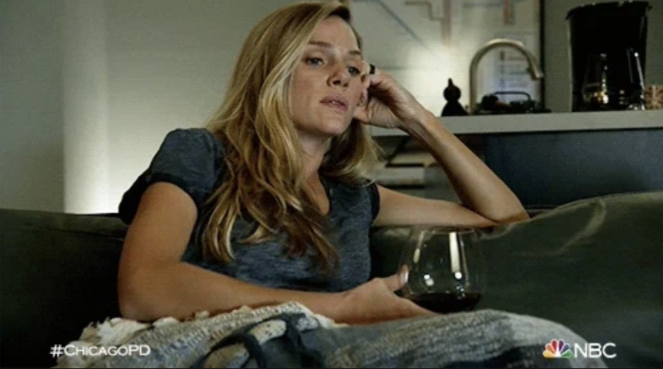 A woman with long hair in a casual shirt sits on a couch, holding a wine glass. The "Chicago PD" logo and "NBC" are in the corners