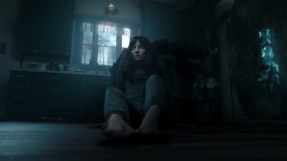 Madison sits on the floor in her kitchen looking terrified in a scene from Malignant.