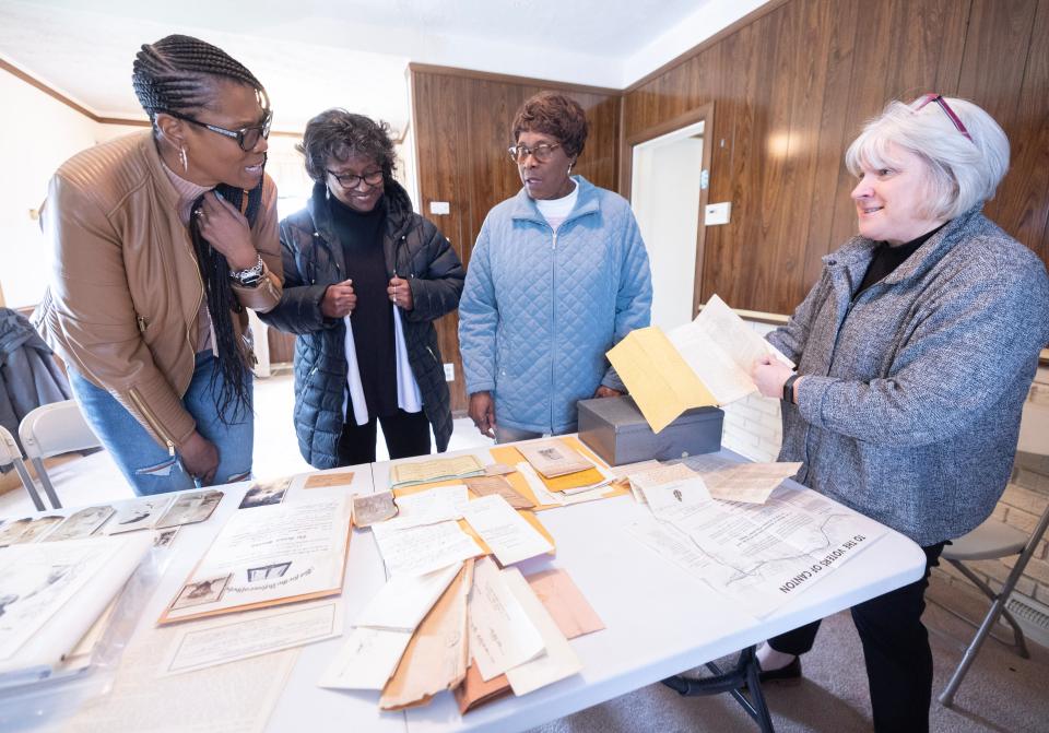 Beth Lechner, CEO of Habitat for Humanity East Central Ohio, far right, presents family memorabilia to Kim Manley, left, Deborah Johnson-Graham, center, and Marie Justice, that was found hidden away in the Johnson family home in Canton.
