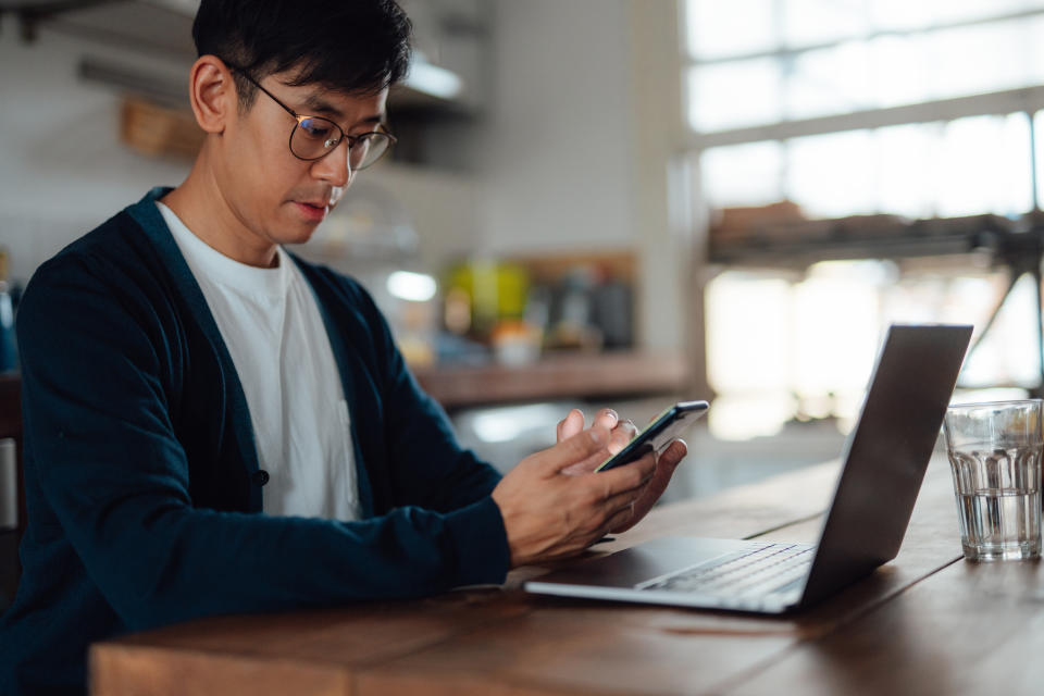 Young Asian adult student learning computer language on laptop and smart phone. Remote working. Online learning. Computer programming.