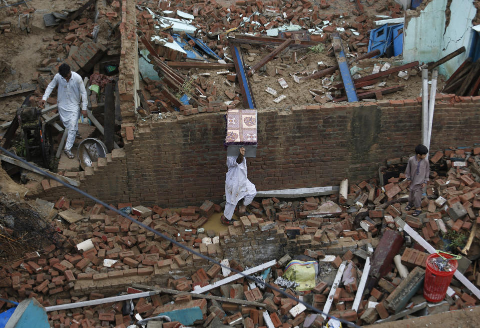 People recover belongings from the rubble of their damaged house caused by a powerful earthquake at Sahang Kikri village near Mirpur, northeastern Pakistan, Wednesday, Sept. 25, 2019. Mourners were burying their dear ones in Pakistan-held Kashmir where a powerful earthquake struck a day before. (AP Photo/Anjum Naveed)
