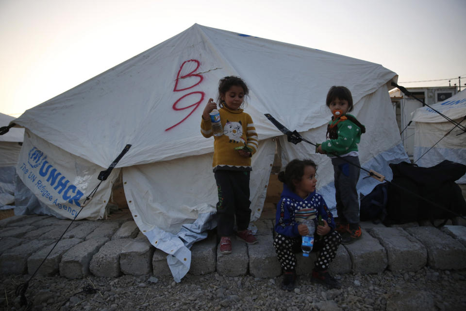 Syrian children who are newly displaced by the Turkish military operation in northeastern Syria, stand outside their tent at the Bardarash camp, north of Mosul, Iraq, Wednesday, Oct. 16, 2019. The camp used to host Iraqis displaced from Mosul during the fight against the Islamic State group and was closed two years ago. The U.N. says more around 160,000 Syrians have been displaced since the Turkish operation started last week, most of them internally in Syria. (AP Photo/Hussein Malla)