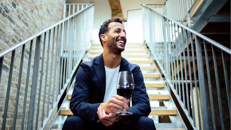 A photo of Daniel Ricciardo holding a glass of wine. 