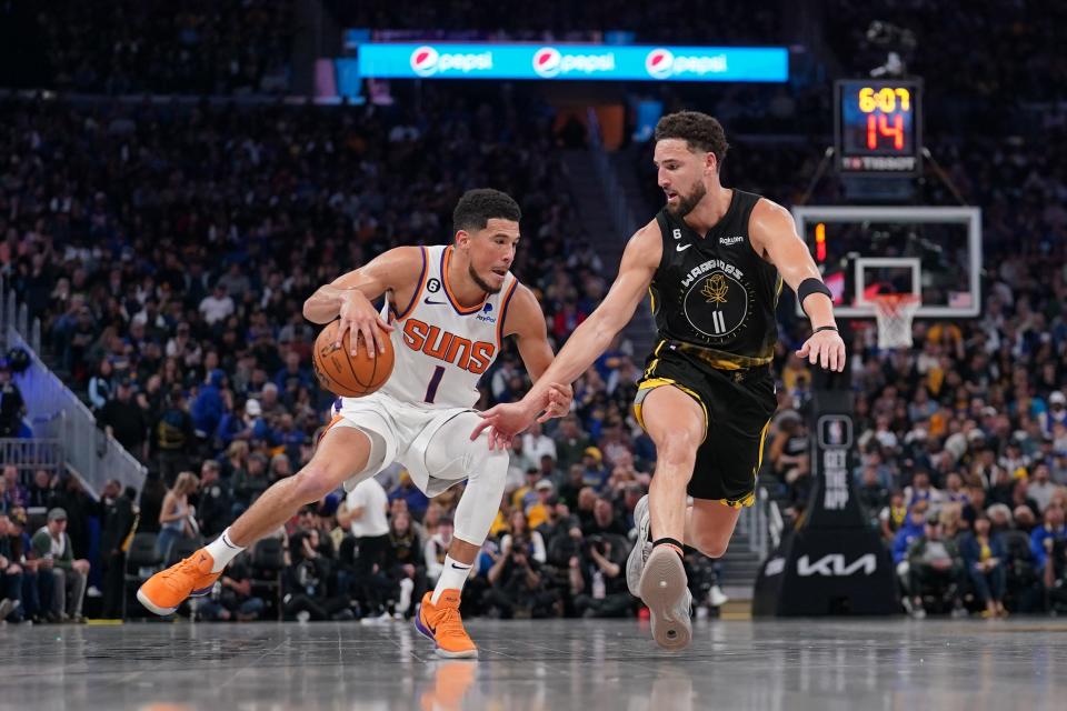 Phoenix Suns guard Devin Booker (1) dribbles the ball next to Golden State Warriors guard Klay Thompson (11) in the third quarter at the Chase Center in San Francisco on March 13, 2023.