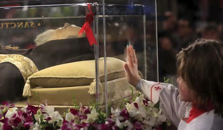 An altar boy touches the glass where the exhumed body of the mystic saint Padre Pio lies in the Catholic church of San Lorenzo fuori le Mura in Rome, February 3, 2016. REUTERS/Yara Nardi