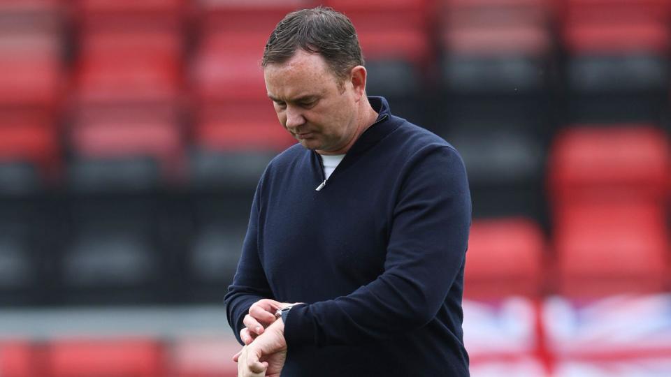 Morecambe boss Derek Adams looks at his watch