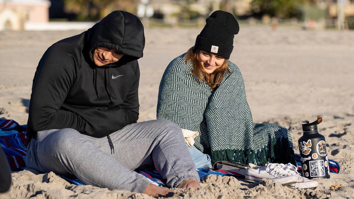 Jordan Stewart, left, and Ashley Rodriguez visit the beach as temperatures dip into the mid-40s on Saturday, Jan. 14, 2023, in Hollywood, Florida. Will visitors need to bundle up in the forecast Oct. 16-17, 2023, cold front forecast for South Florida? Depends on what you consider cold.