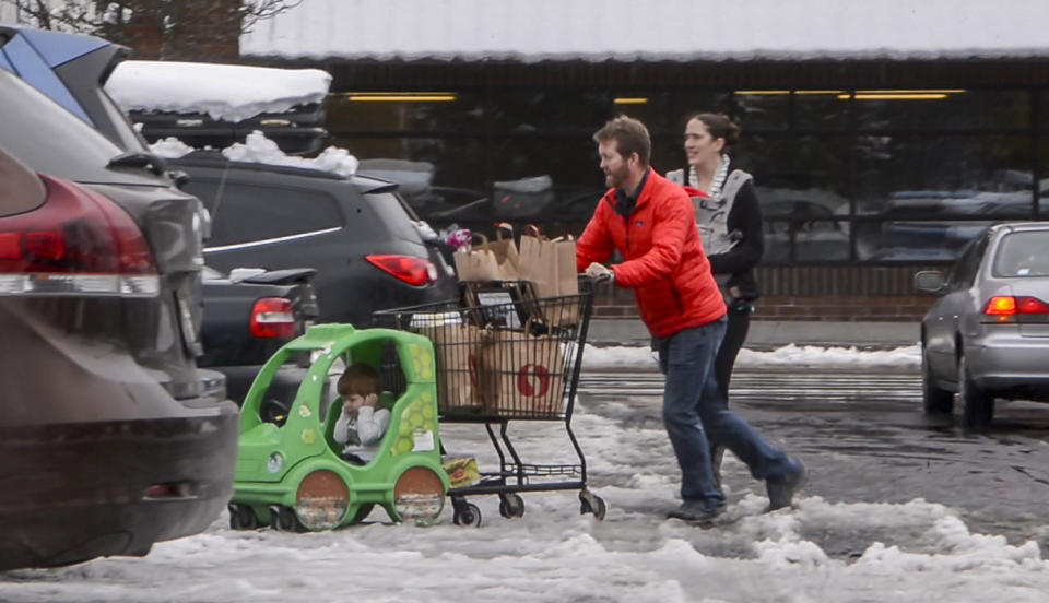 Jesse and Sarah Fees have their children along on a trip in North Tacoma, Wash., to restock their kitchen, Sunday, Feb. 10, 2019. Pacific Northwest residents who are more accustomed to rain than snow were digging out from a winter storm and bracing for more on Sunday. (Peter Haley/The News Tribune via AP)