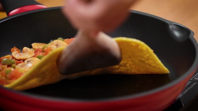 flipping omelette into half with wooden spatula