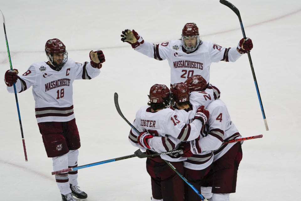 Massachusetts players gather around Zac Jones (24) after he scored against Minnesota Duluth during the first period of an NCAA men's Frozen Four hockey semifinal in Pittsburgh, Thursday, April 8, 2021. (AP Photo/Keith Srakocic)