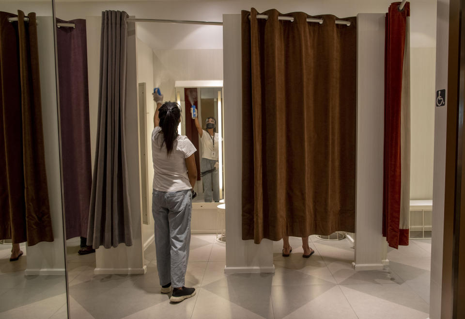 An employee sanitizes a fitting room at the upmarket shopping mall Siam Paragon in Bangkok, Thailand, Sunday, May 17, 2020. Thai authorities allowed department stores, shopping malls and other businesses to reopen from Sunday, selectively easing restrictions meant to combat the coronavirus. (AP Photo/ Gemunu Amarasinghe)