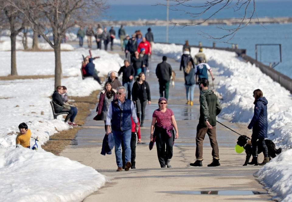 People take advantage of the warm weather as they walk along the Lake Michigan lakefront near Veterans Park in Milwaukee on Saturday, Feb. 27, 2021.