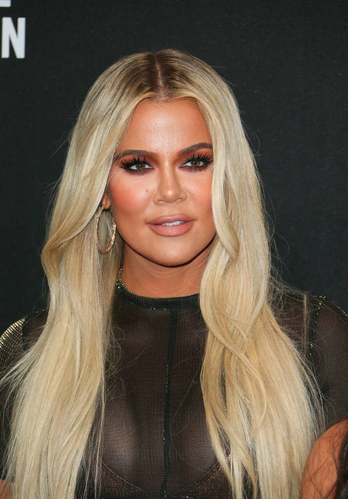 Khloe Kardashian wearing a sheer top and hoop earrings