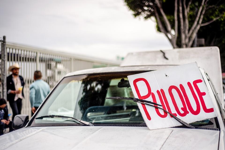 A truck with a sign reading "pulque" on its windshield.