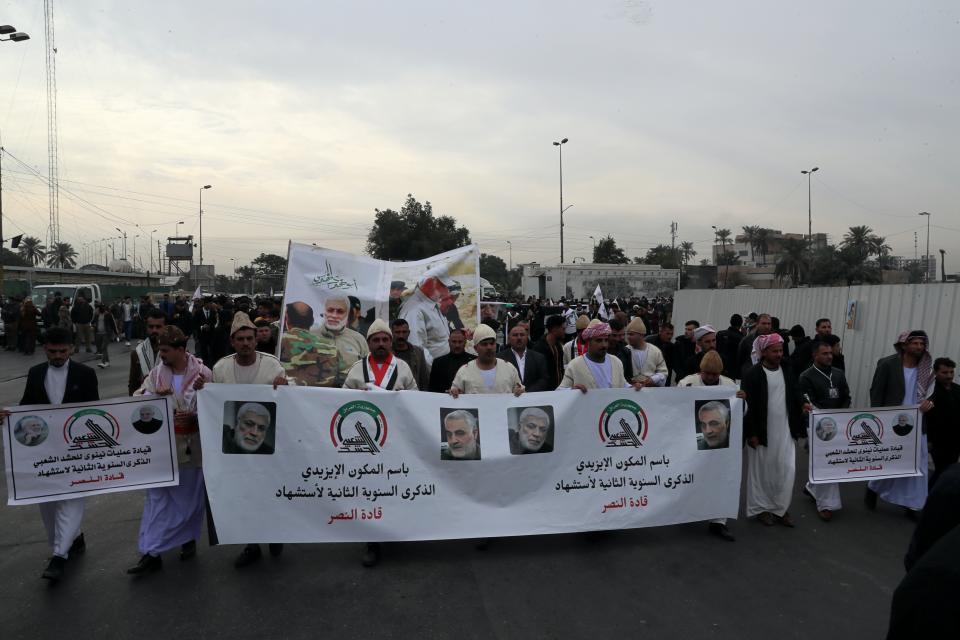 Supporters and members of the Popular Mobilization Forces hold posters of a powerful Iranian general and a top Iraqi militia leader in Baghdad, Iraq, Saturday, Jan. 1, 2022. Hundreds rally in Baghdad on Soleimani assassination anniversary, chanting anti-American slogans, hundreds of people rallied in in the Iraqi capital on the first day of the year Saturday to mark the anniversary of the killing of a powerful Iranian general and a top Iraqi militia leader in a U.S. drone strike. (AP Photo/Khalid Mohammed)