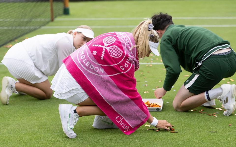 Katie Boulter and Daria Saville help to tidy up the court