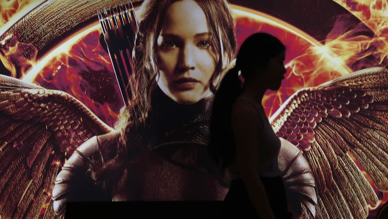 A woman is silhouetted against a billboard of the movie The Hunger Games: Mockingjay - Part 1 in Bangkok, Thailand, Thursday, Nov. 20, 2014.
