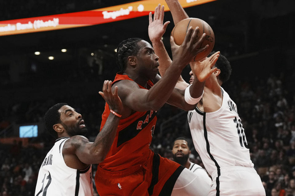 Toronto Raptors forward O.G. Anunoby (3) shoots as Brooklyn Nets' Kyrie Irving, right, and Ben Simmons defend during the first half of an NBA basketball game Wednesday, Nov. 23, 2022, in Toronto. (Chris Young/The Canadian Press via AP)
