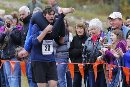 Brian Chin carries Kerrie Keller while competing in the North American Wife Carrying Championship at Sunday River ski resort in Newry, Maine October 11, 2014. REUTERS/Brian Snyder