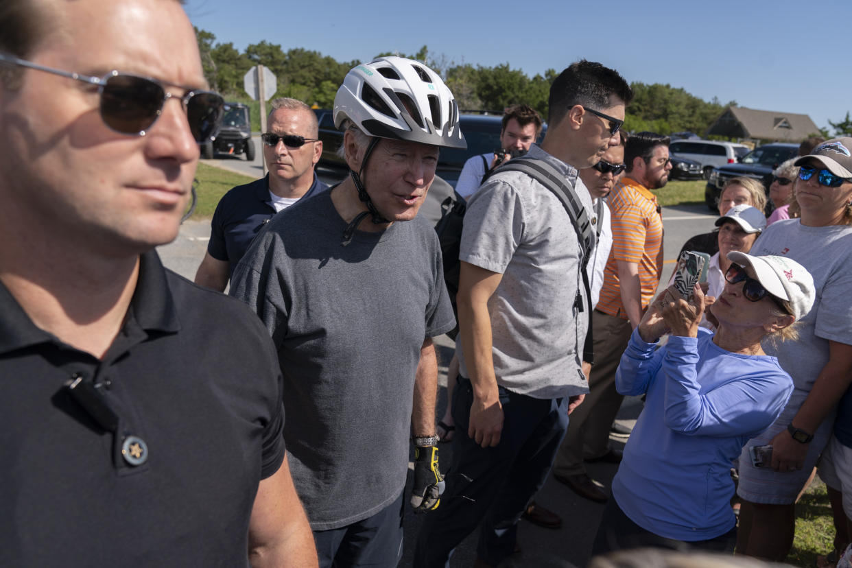President Joe Biden, surrounded by U.S. Secret Service agents, talks to a crowd after falling from his bike on a trail at Gordons Pond in Rehoboth Beach, Del., Saturday, June 18, 2022. Biden is spending the weekend at his Rehoboth Beach home. (AP Photo/Manuel Balce Ceneta)