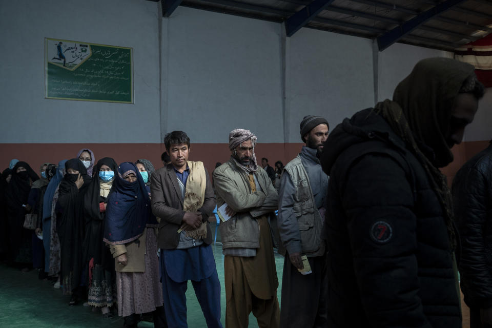 People wait in a line to receive cash at a money distribution organized by the World Food Program (WFP) in Kabul, Afghanistan, Wednesday, Nov. 3, 2021. Afghanistan's economy is fast approaching the brink and is faced with harrowing predictions of growing poverty and hunger. (AP Photo/Bram Janssen)