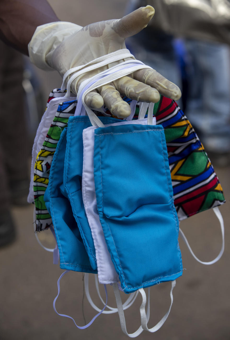 A street vendor wearing surgical glove, to protect against coronavirus, sells face musks at a minibus taxi station in Johannesburg, South Africa, Thursday, March 26, 2020. South Africa goes into a nationwide lockdown for 21 days in a few hours, in an effort to mitigate the spread to the coronavirus. (AP Photo/Themba Hadebe)