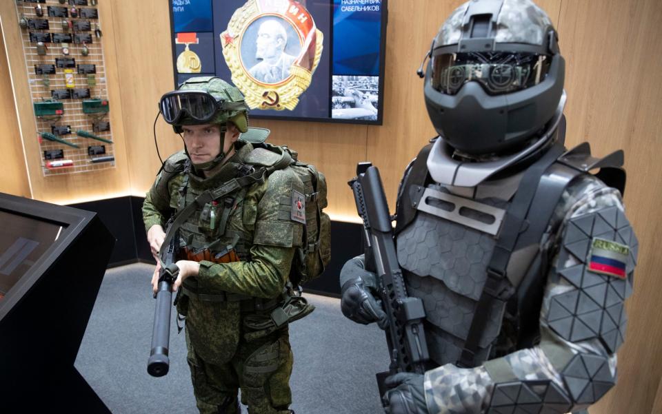 A soldier (left) wears a working sample of passive exoskeleton combat gear next to a mannequin dressed in a prototype of active exoskeleton combat gear from Rostec in 2018 - AP