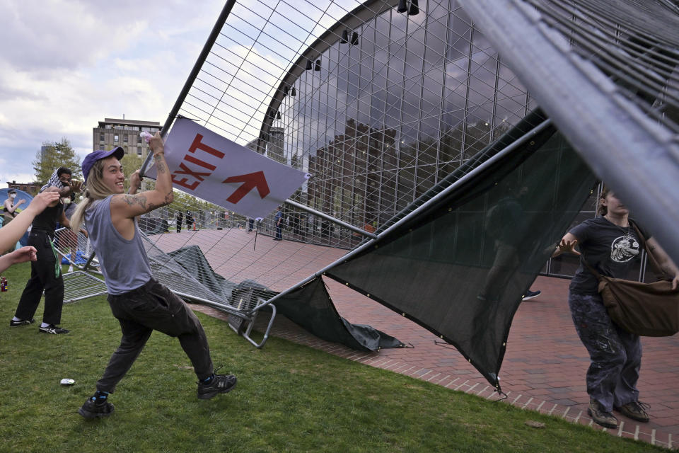 Manifestantes quitan barricadas que habían sido colocadas afuera de un campamento de protesta propalestino en el Instituto de Tecnología de Massachusetts (MIT por sus siglas en inglés), el lunes 6 de mayo de 2024, en Cambridge, Massachusetts. (AP Foto/Josh Reynolds)