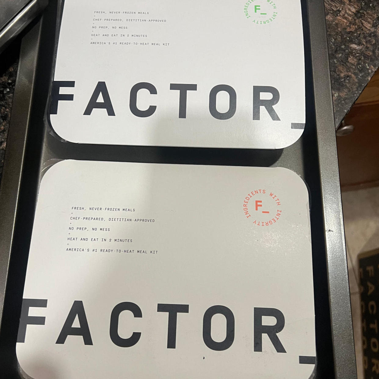 Two Factor meals still in packaging on a pan. (Courtesy of Mili Godio; Factor)