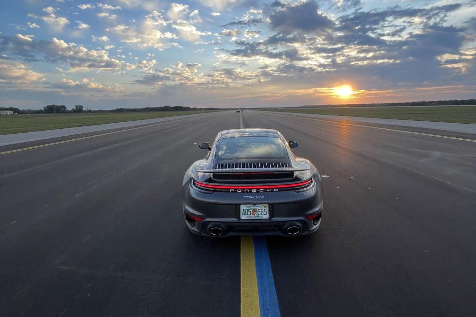 a car on a road with the sun setting