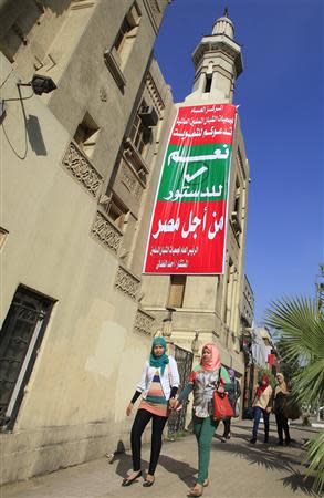 Girls walk in front of a banner urging participation in the upcoming referendum, which reads: "General status of the associations of young Muslims worldwide invites you to vote (yes on the Constitution) for 'Yes for Egypt's future", in downtown Cairo January 6, 2014. REUTERS/Amr Abdallah Dalsh