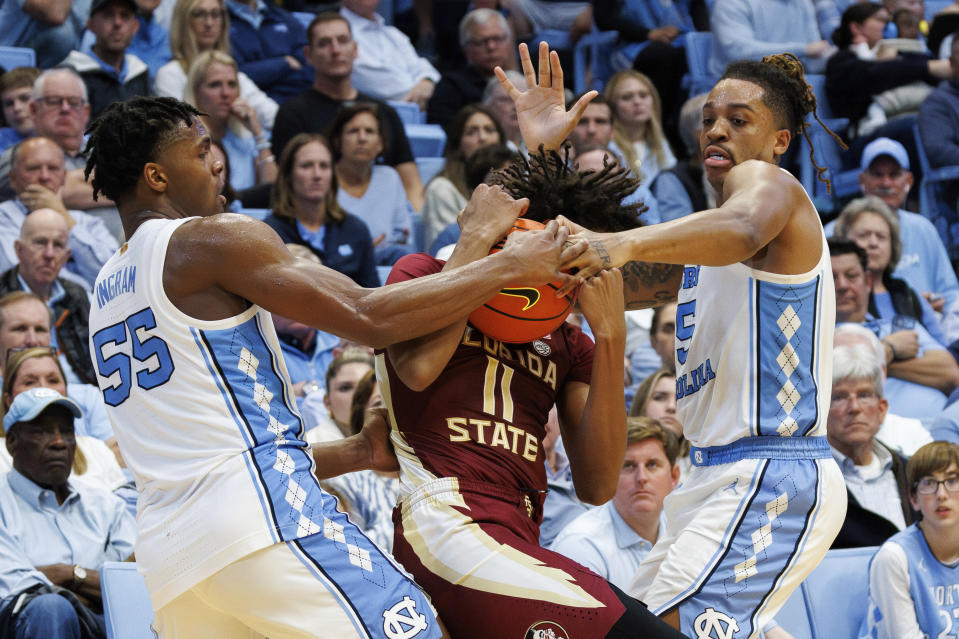 Florida State's Baba Miller (11) tries to handle the ball as North Carolina's Harrison Ingram (55) and Armando Bacot (5) defend during the second half of an NCAA college basketball game in Chapel Hill, N.C., Saturday, Dec. 2, 2023. (AP Photo/Ben McKeown)